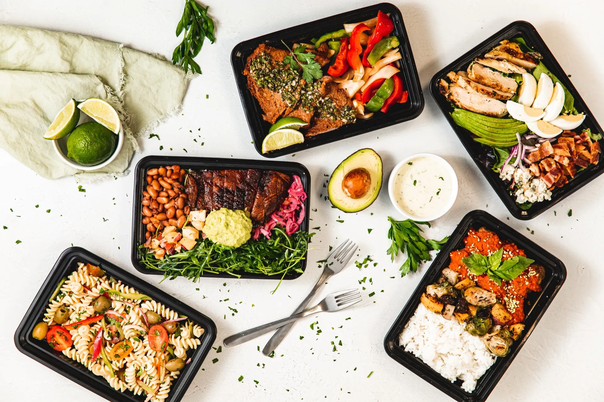 Midday deli lunch spread with sliders, wraps, salads, and a to-go box at Deli Nerds Costa Mesa